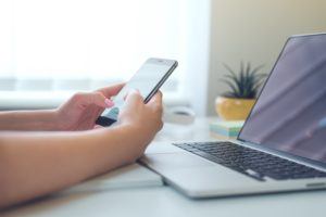 stock photo of a women holding phone in front of laptop