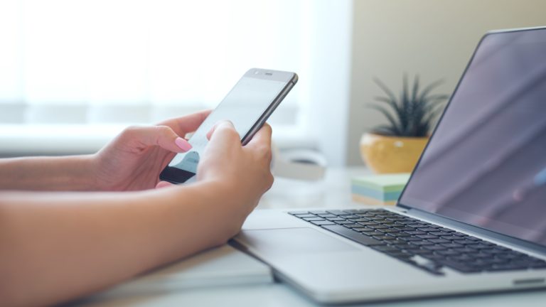 stock photo of a women holding phone in front of laptop