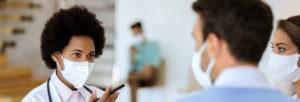 female doctor talking to couple with face masks