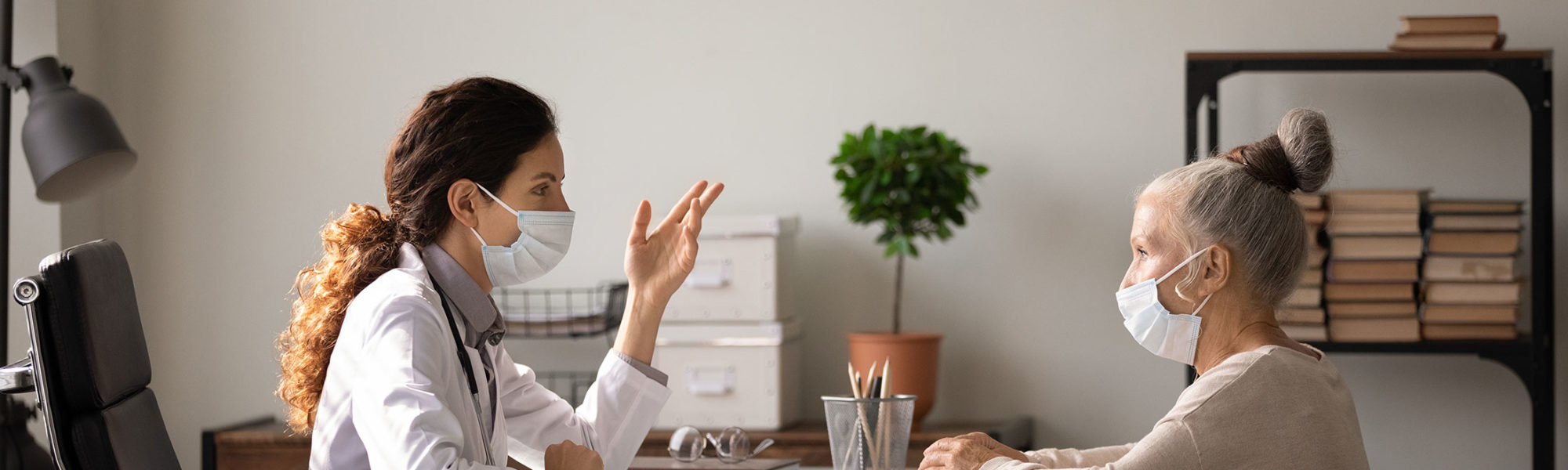 stock photo of patient and doctor talking in office with face mask on