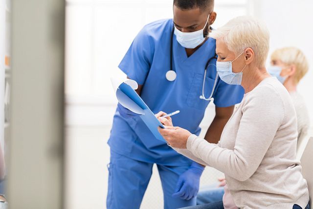 male nurse helping older female patient with forms