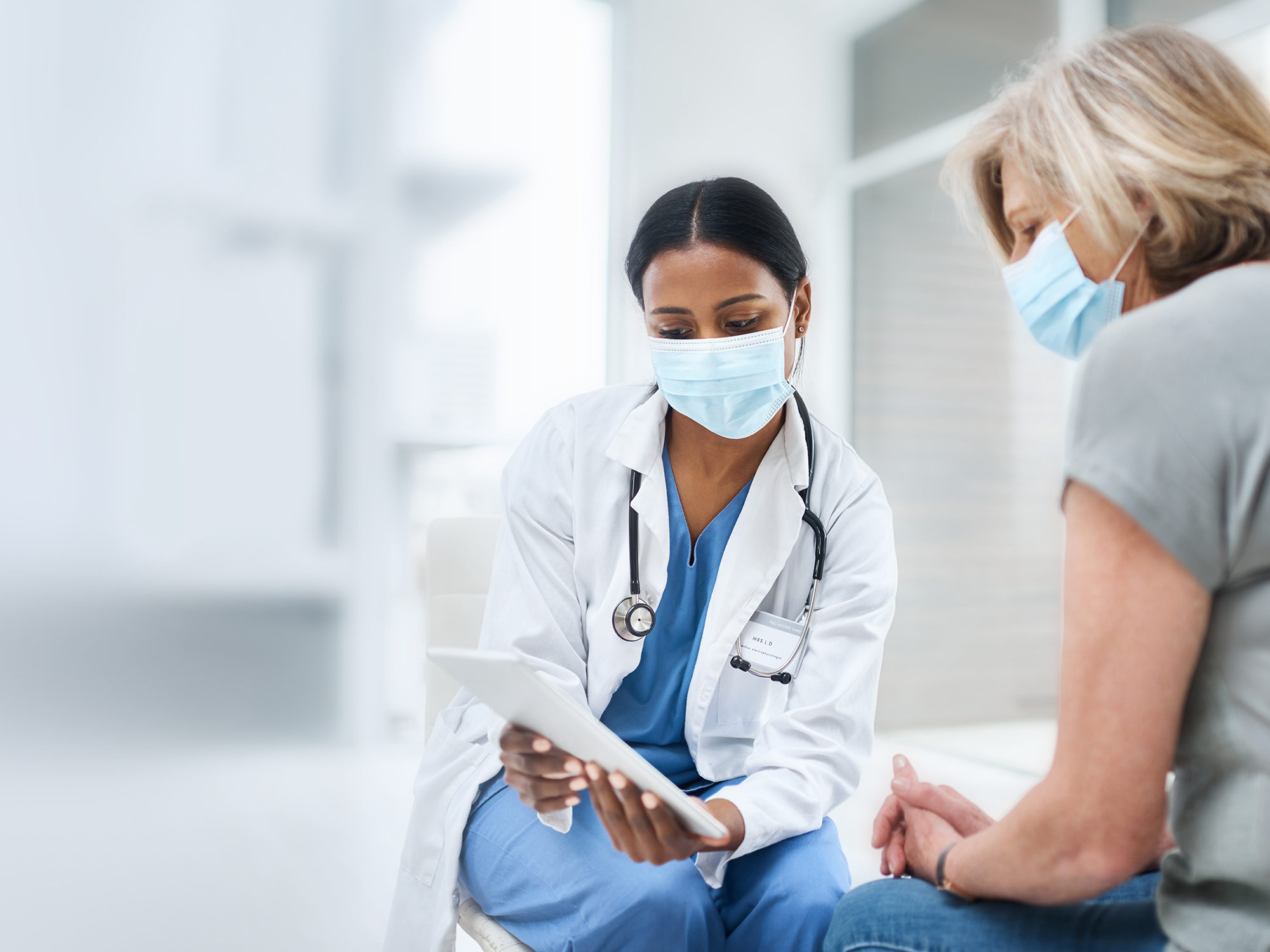 stock photo with black female doctor showing white female patient tablet