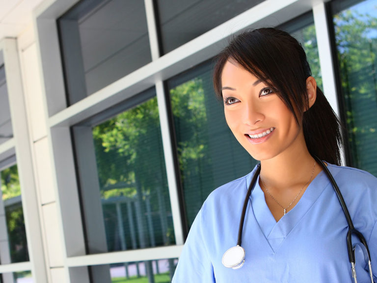 Doctor standing outside near the hospital wearing her stethoscope around her neck